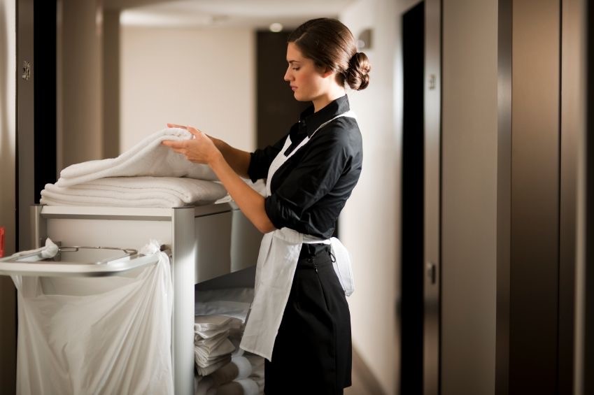 Photo dans un hotel d'une femme de ménage changeant des serviettes de bain.